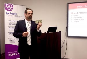 Kenneth Hitchner, public relations and social media director at Creative Marketing Alliance, holds up a dollar bill as an example of branding.